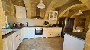 Une cuisine rustique avec des murs en pierre, des meubles blancs et un îlot central.