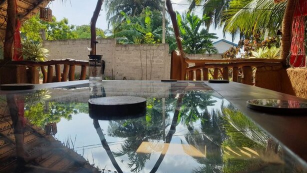 Una piscina con cubierta de cristal y una fuente central, rodeada de barandillas de madera y palmeras.