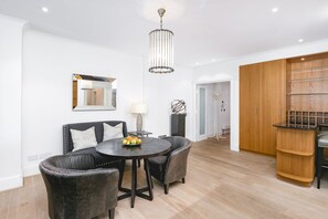 A modern dining area with a round table, two upholstered chairs, a chandelier, and a wooden cabinet. - ' Luxury & Spacious AirCondisioned 4 Bed 4 Bath Apartment ' (London)