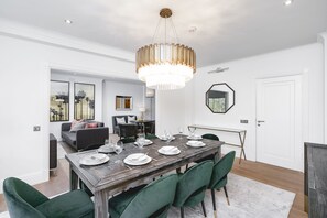 A dining area with a wooden table set for six, green upholstered chairs, and a modern chandelier. - ' Luxury & Spacious AirCondisioned 4 Bed 4 Bath Apartment ' (London)