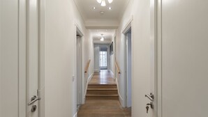 A hallway with white walls, wooden flooring, and a staircase leading to another room. - ' Luxury & Spacious AirCondisioned 4 Bed 4 Bath Apartment ' (London)