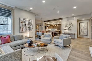 A modern living room with a grey sofa, armchairs, a coffee table, and artwork on the walls.
