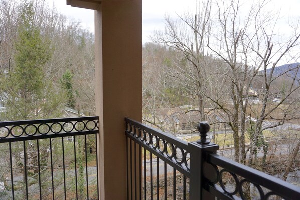 Un balcon doté d’une rambarde en métal, donnant sur un quartier résidentiel avec des arbres et des maisons.