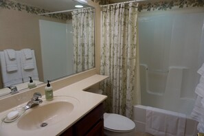 Une salle de bain équipée d’un lavabo, d’un miroir, de toilettes et d’un rideau de douche.