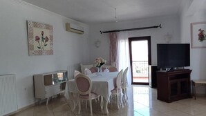A spacious living room with a dining area, a television, and a balcony. - Chrisa's Beautiful Apartment  (Chania)