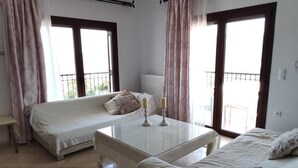 A room with two beds, a small table, and a window. - Chrisa's Beautiful Apartment  (Chania)