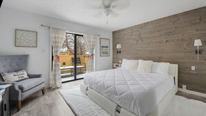 Une chambre avec un grand lit, une chaise, un bureau et une vue sur l’extérieur.