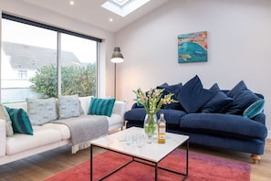 En moderne stue med sofa, sofabord og et billede på væggen.