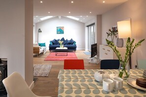 Ein modernes Wohnzimmer mit einer Couch, einem Couchtisch und einem Essbereich mit Tisch für zwei Personen.