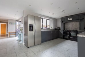 A modern kitchen with stainless steel appliances, dark cabinetry, and a granite countertop.