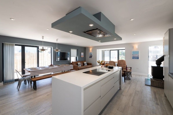 Una cocina moderna con una isla central, electrodomésticos integrados y una zona de comedor con banco.