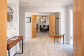 A hallway leading to a living area with a sofa and a coffee table, wooden doors, and a bench. - Trem Y Don:  A beachside holiday home for 10 guests (Rhosneigr)