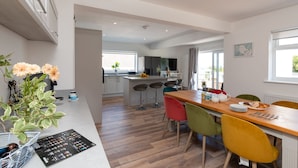 Een moderne keuken met een centraal eiland, barstoelen en een eettafel met kleurrijke stoelen.