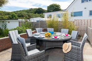 Rattan outdoor dining table and chairs in the enclosed garden, pet-friendly holiday home two minutes from Benllech Beach, Anglesey - Sandaig: Pet-Friendly Holiday Home Near Benllech Beach (Benllech)