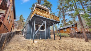 A two-story wooden cabin with a balcony, surrounded by trees and a wooden fence. - CRESCENT TREE CABIN CLOSE TO BEAR MOUNTAIN, GOLF COURSE  AND THE ZOO (Big Bear Lake)