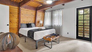 A bedroom with a bed, a bench, a ceiling fan, and a door with a view of the outdoors. - CRESCENT TREE CABIN CLOSE TO BEAR MOUNTAIN, GOLF COURSE  AND THE ZOO (Big Bear Lake)