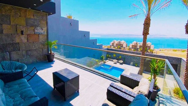 Eine Dachterrasse mit Pool, Sitzgelegenheiten im Freien und Meerblick.