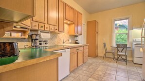 A kitchen with wooden cabinets, a dishwasher, a coffee maker, and a window with a view of greenery outside. - Welcoming Helena Hideaway ~ 2 Mi to Downtown (Helena)
