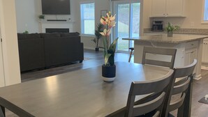 Eine moderne Küche mit Essbereich, ausgestattet mit einem Flachbildfernseher, Deckenventilator, Pendelleuchten und einem Blumentopf.