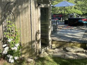 A wooden deck with a stone pathway, outdoor furniture, and a small shed. - Little Farmhouse Cottage - Country Near the Coast (South Kingstown)
