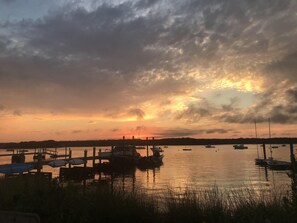 Eine Marina mit vertäuten Booten, eine Anlegestelle mit Sonnenschirmen und ein Sonnenuntergang im Hintergrund.