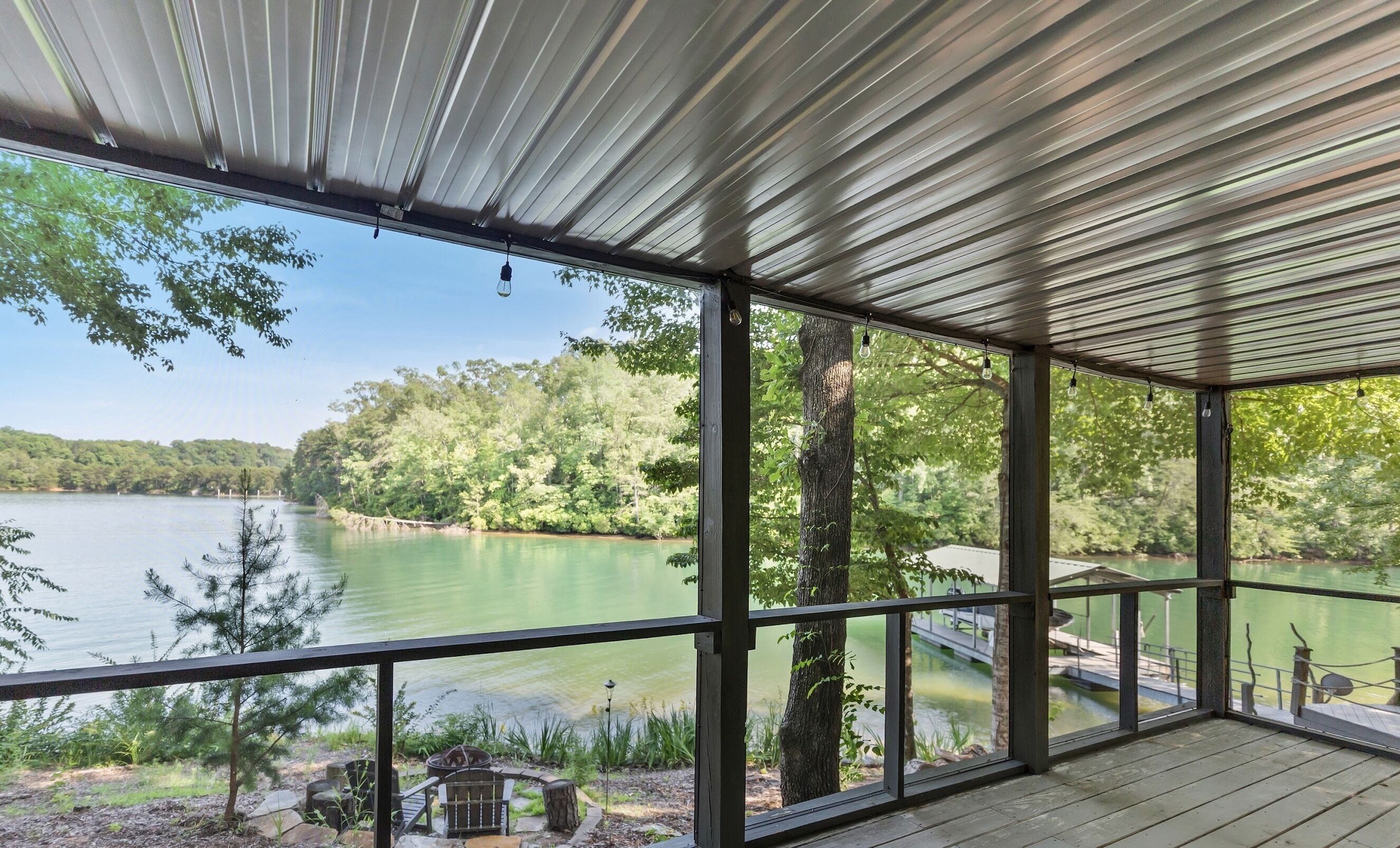 A covered outdoor deck with a view of a lake and forest.