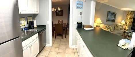 Una cocina moderna con comedor, una sala de estar con sofá y lámpara, y un letrero que dice "Life is good at the beach".