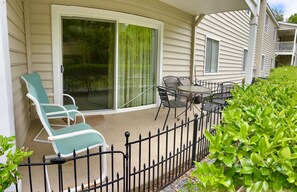 A covered patio with a sliding glass door, outdoor furniture, and a metal fence. - E11 Peaceful 2/2 Ground Level, New Shower & Floors (St. Simons Island)