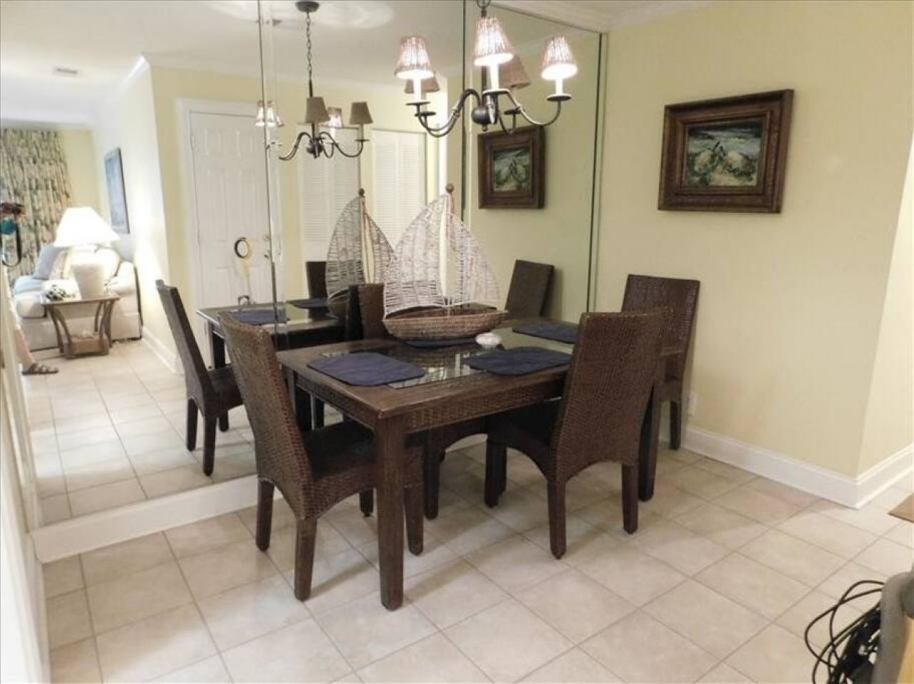 A dining area with a dark wooden table, wicker chairs, and a chandelier.