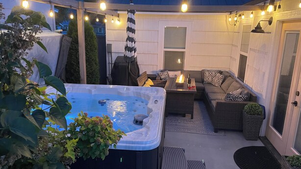 En uteplats med en bubbelpool, sittgrupp och ljusslingor.