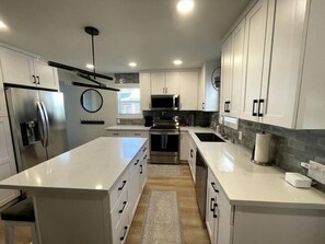 A modern kitchen with white cabinetry, stainless steel appliances, and a central island.