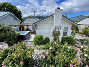 A house with a hot tub, patio furniture, and a garden with roses.
