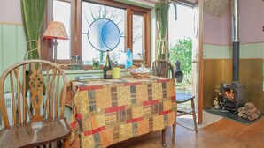 A cozy room with a wooden table, chairs, a window with curtains, a fireplace, and a view of the outdoors. - The Observatory-UK41754 (Tresawson, near Looe)