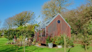 A rustic wooden structure with a sloped roof, surrounded by a well-maintained garden with various plants and a lawn. - The Observatory-UK41754 (Tresawson, near Looe)