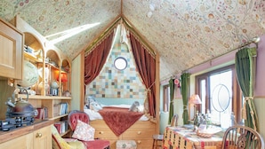A cozy, well-lit room with a wooden ceiling, a bed with a red canopy, a dining table with a quilt, and a wooden chair. - The Observatory-UK41754 (Tresawson, near Looe)