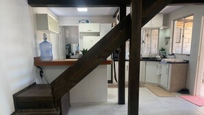 Eine Küche mit einer Holztreppe, Fliesenboden und einem großen Wasserspender.