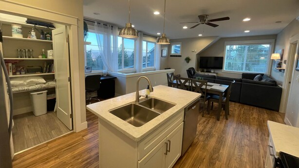 A modern kitchen with a central island, wooden flooring, and pendant lighting. - Edgewood Escape | Mt. Rainier View| EV Charger - Central (Edgewood)