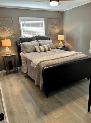 Relax in this stylish bedroom with a comfortable bed, bedside table, and window with blinds.