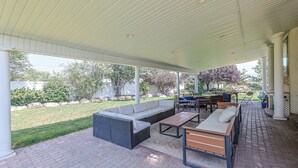 A covered patio area with outdoor furniture, including sofas and a dining table, and a view of the garden and trees. - Private/clean guest suite, bath, kitchen & laundry (South Jordan)