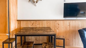 A room with a wooden table, benches, a mounted ram skull, and a TV on the wall. - Awesome Location Steam Shower Hottub (Telluride)