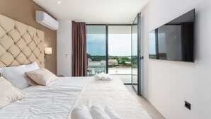 A modern hotel room with a large bed, a TV, and a balcony with a view. - Luxury Villa Borealis with Pool (Ližnjan)