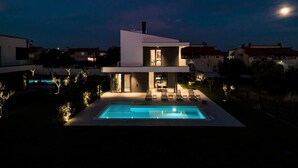 A modern two-story house with a swimming pool, outdoor seating, and a view of the night sky. - Luxury Villa Monroe with Pool (Vodnjan)