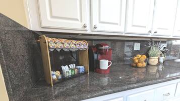 Eine Küche mit einer Kaffeestation, einer roten Keurig-Kaffeemaschine, einer Orangenschale und einer Blumentopf-Pflanze.