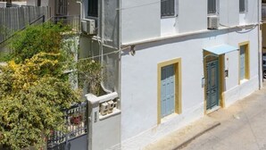 A two-story building with a balcony on the upper floor, a gated entrance, and a small garden area. - Mary's Central Beachside Mansion- with large Terrace and Balcony  (Agios Nikolaos)