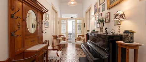 A hallway with a piano, wooden furniture, and a mirror.