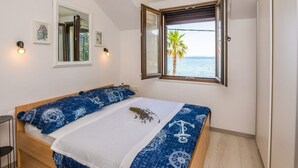 Ein Schlafzimmer mit einem Bett, einem Fenster mit Meerblick und einem kleinen Tisch.