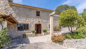 A stone building with a wooden door, a window with bars, and a small balcony. - Charming Pollensa Villa | Beautiful Views Of the Tramuntana Mountains | La. (Pollensa)