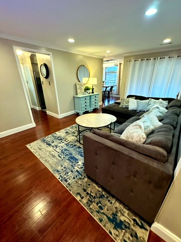 A living room with a brown sofa, a round coffee table, and a patterned rug.