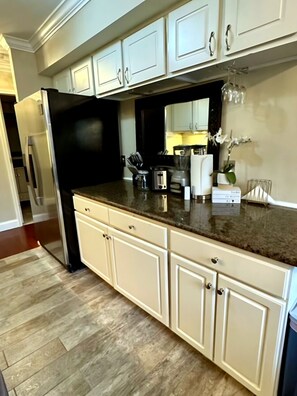 A kitchen with white cabinetry, a black refrigerator, and a granite countertop.