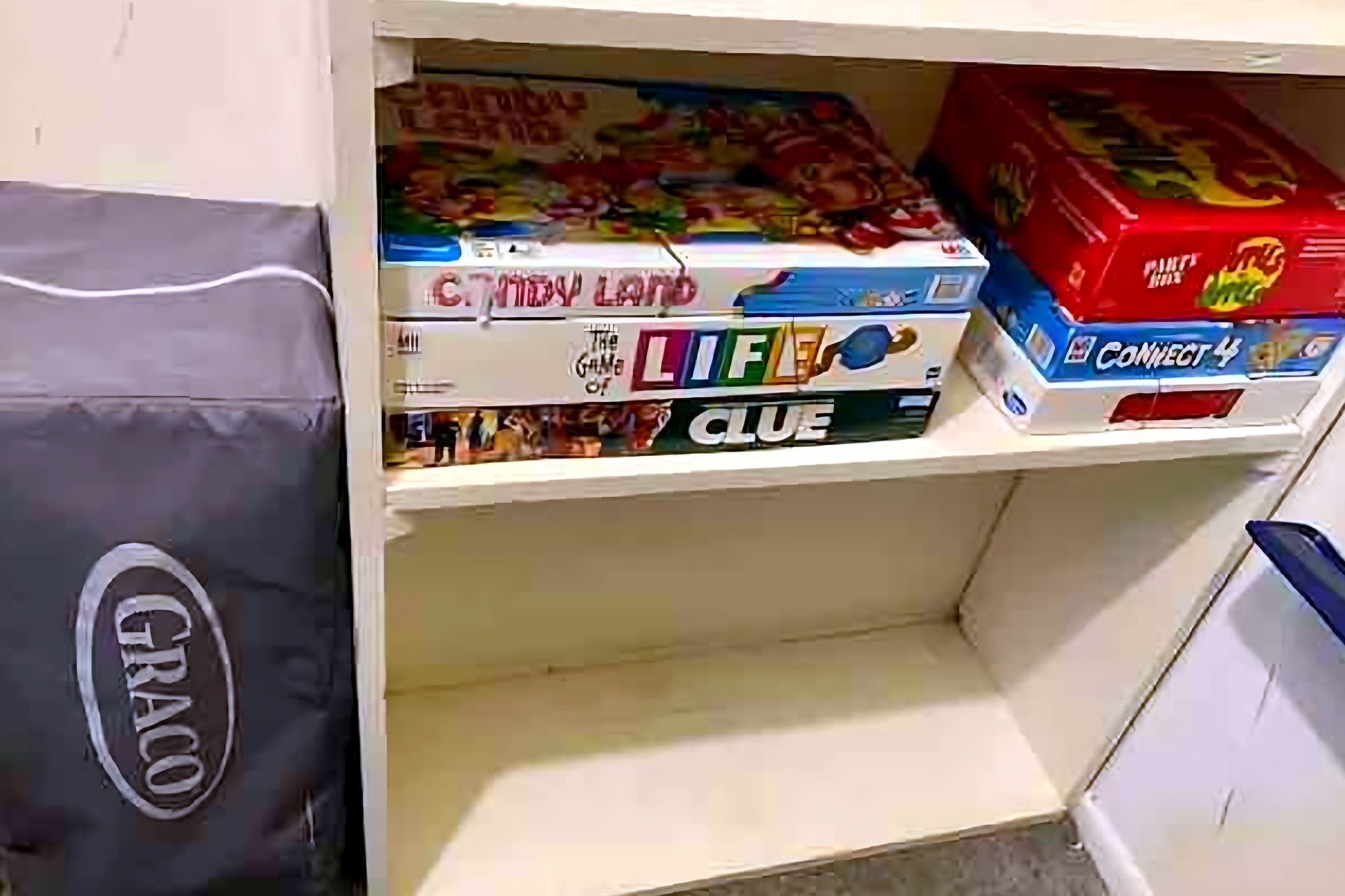 A shelf with board games including Candy Land, Life, and Clue.